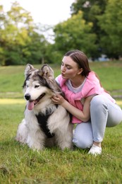Photo of Woman with her cute Alaskan malamute dog on green grass outdoors