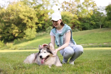 Photo of Smiling woman with her cute Alaskan malamute dog on green grass outdoors