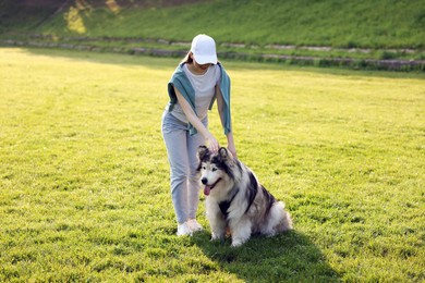 Photo of Woman with her cute Alaskan malamute dog on green grass outdoors in morning
