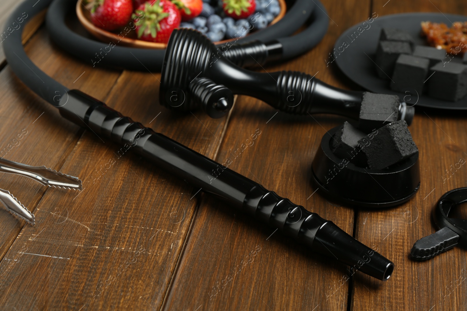 Photo of Traditional hookah parts, charcoal cubes and berries on wooden table