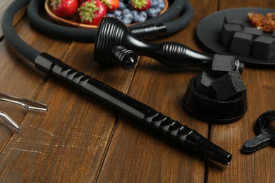 Photo of Traditional hookah parts, charcoal cubes and berries on wooden table