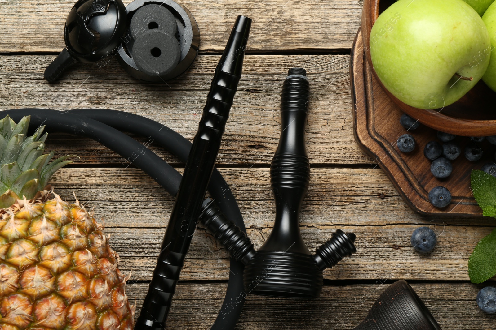 Photo of Traditional hookah parts, charcoal rings, fruits, blueberries and mint on wooden table, flat lay