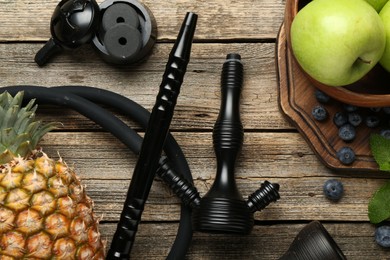 Photo of Traditional hookah parts, charcoal rings, fruits, blueberries and mint on wooden table, flat lay