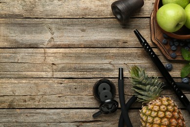 Photo of Traditional hookah parts, charcoal rings, fruits, blueberries and mint on wooden table, flat lay. Space for text