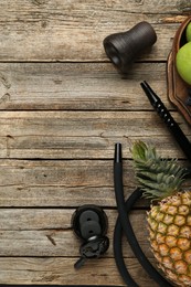 Photo of Traditional hookah parts, charcoal rings and pineapple on wooden table, flat lay. Space for text