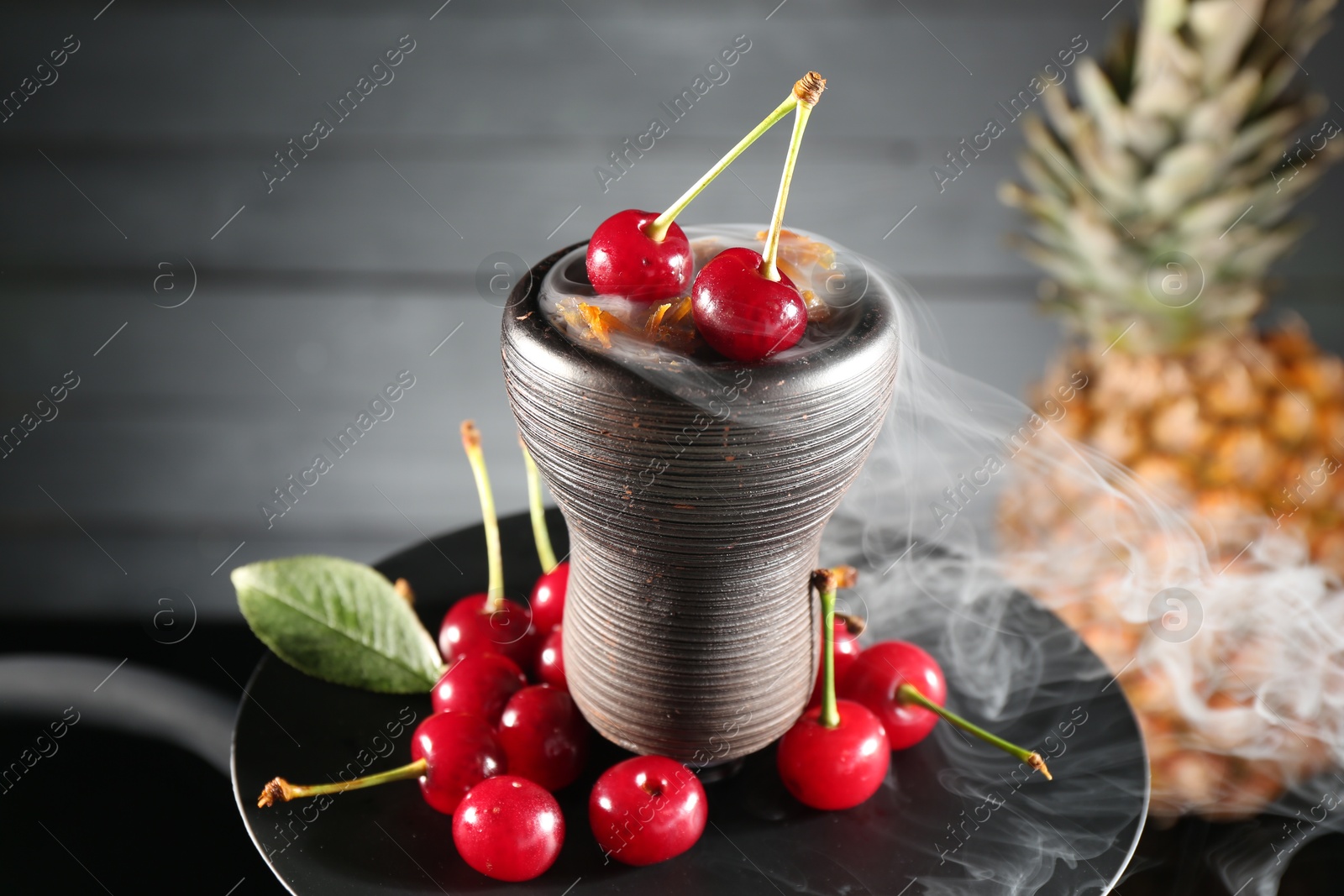 Photo of Hookah with cherries and smoke on black background, closeup