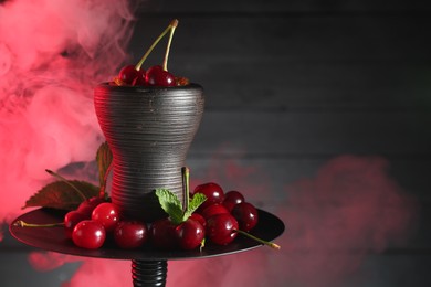 Photo of Hookah with cherries and smoke on black background, closeup. Space for text