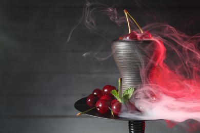 Photo of Hookah with cherries and smoke on black background, closeup. Space for text