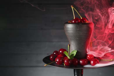 Photo of Hookah with cherries and smoke on black background, closeup. Space for text