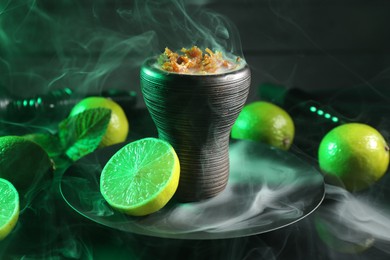 Photo of Hookah bowl with limes, mint and smoke on black table, closeup
