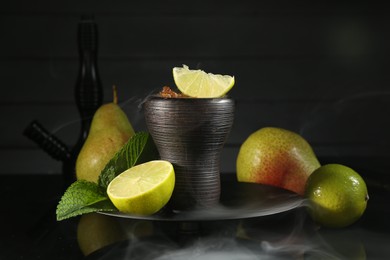 Photo of Hookah bowl with fruits, mint and smoke on black table, closeup