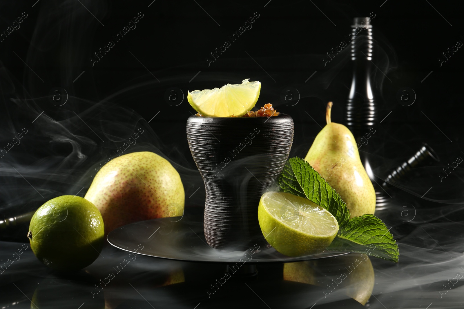 Photo of Hookah bowl with fruits, mint and smoke on black table, closeup