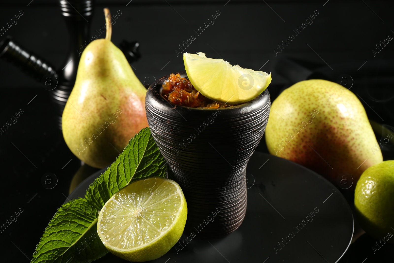 Photo of Hookah bowl with fruits, mint and smoke on black table, closeup