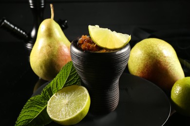 Photo of Hookah bowl with fruits, mint and smoke on black table, closeup