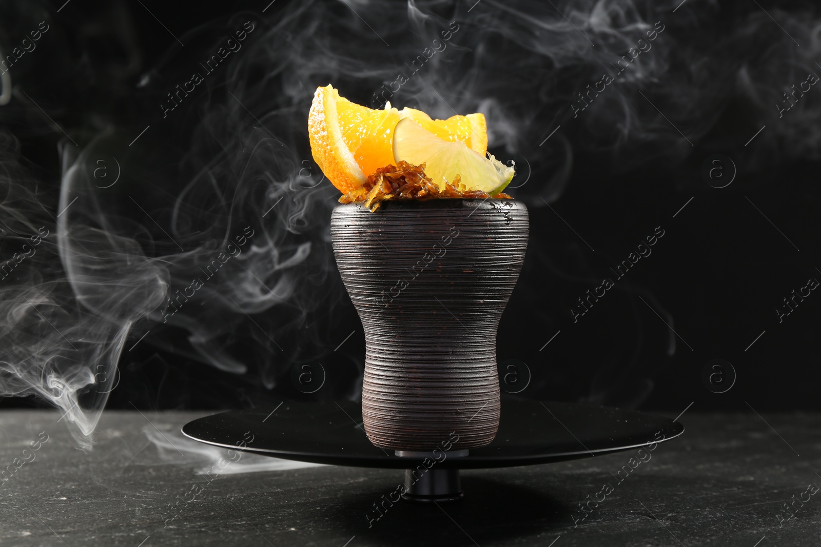 Hookah bowl with citrus fruits and smoke on black table, closeup Photo of Hookah bowl with citrus fruits and smoke on black table, closeup