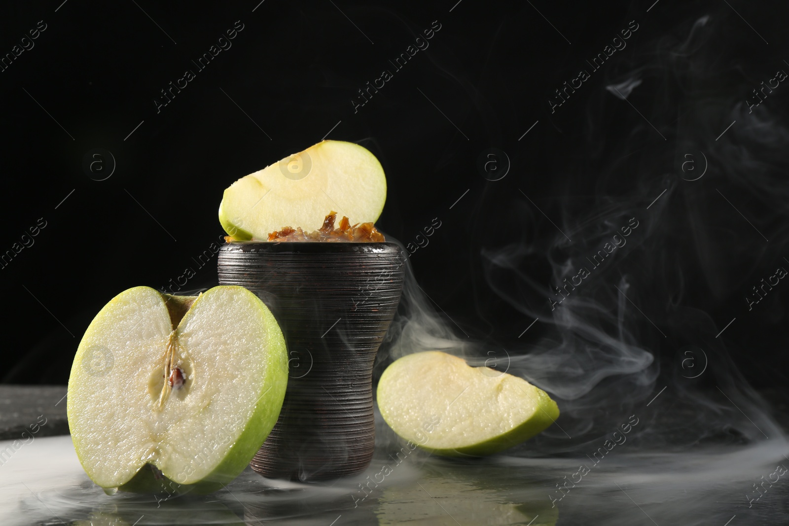 Hookah bowl with apple pieces and smoke on black table, closeup. Space for text Photo of Hookah bowl with apple pieces and smoke on black table, closeup. Space for text
