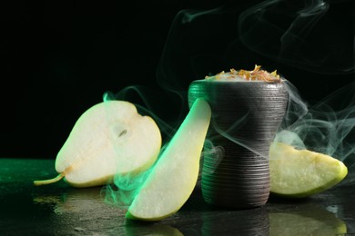 Photo of Hookah bowl with pear pieces and smoke on black table, closeup