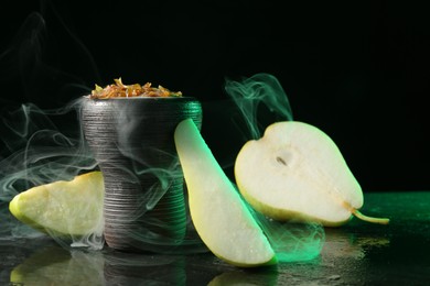 Photo of Hookah bowl with pear pieces and smoke on black table, closeup