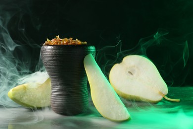 Photo of Hookah bowl with pear pieces and smoke on black table, closeup