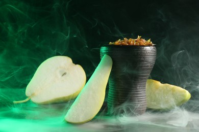 Photo of Hookah bowl with pear pieces and smoke on black table, closeup