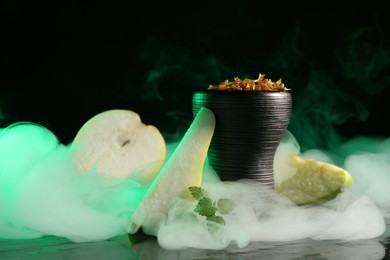 Photo of Hookah bowl with pear pieces, mint and smoke on black table, closeup