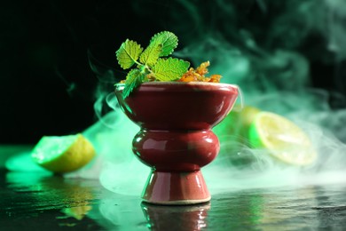 Photo of Hookah bowl with limes, mint and smoke on black table, closeup