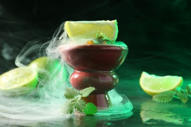 Photo of Hookah bowl with limes, mint and smoke on black table, closeup