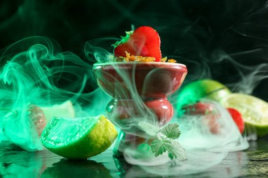Photo of Hookah bowl with limes, strawberries, mint and smoke on black table, closeup