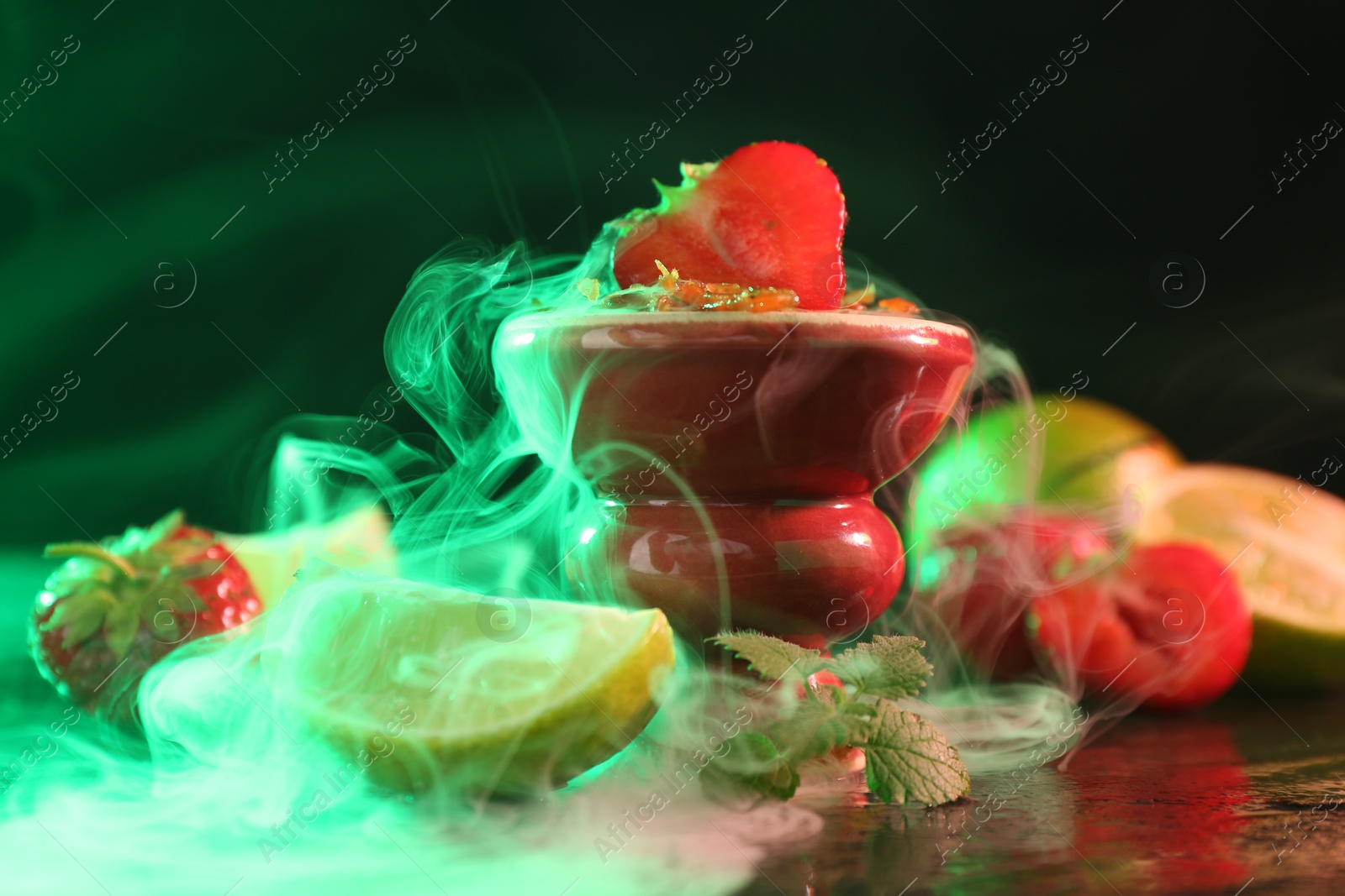 Hookah bowl with limes, strawberries, mint and smoke on black table, closeup Photo of Hookah bowl with limes, strawberries, mint and smoke on black table, closeup