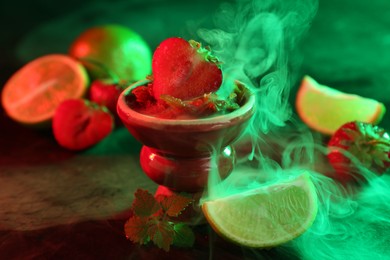 Photo of Hookah bowl with limes, strawberries, mint and smoke on black table, closeup