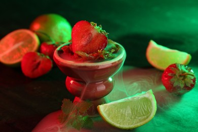 Photo of Hookah bowl with limes, strawberries, mint and smoke on black table, closeup