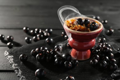 Photo of Hookah bowl with currants and smoke on black table, closeup