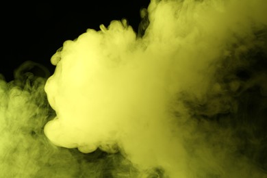 Photo of Hookah smoke in yellow light on black background, closeup