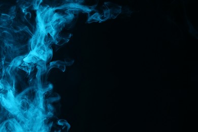 Photo of Hookah smoke in blue light on black background, closeup. Space for text