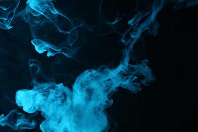 Photo of Hookah smoke in blue light on black background, closeup