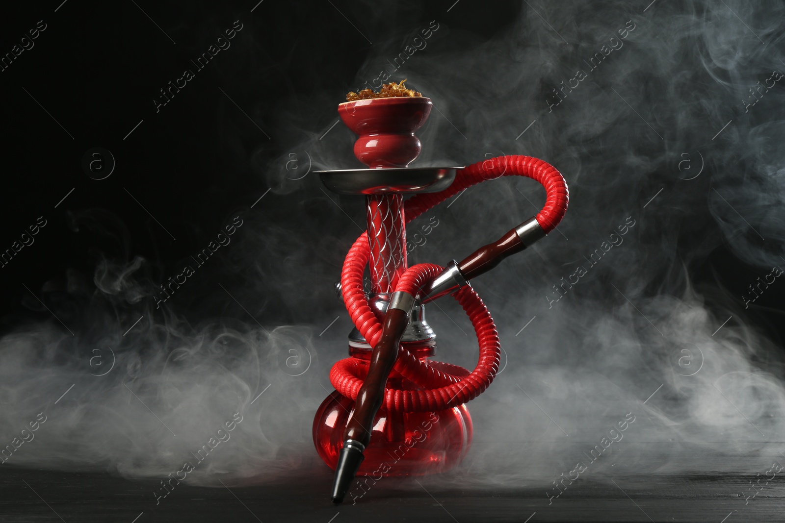 Hookah on wooden table with smoke against black background Photo of Hookah on wooden table with smoke against black background