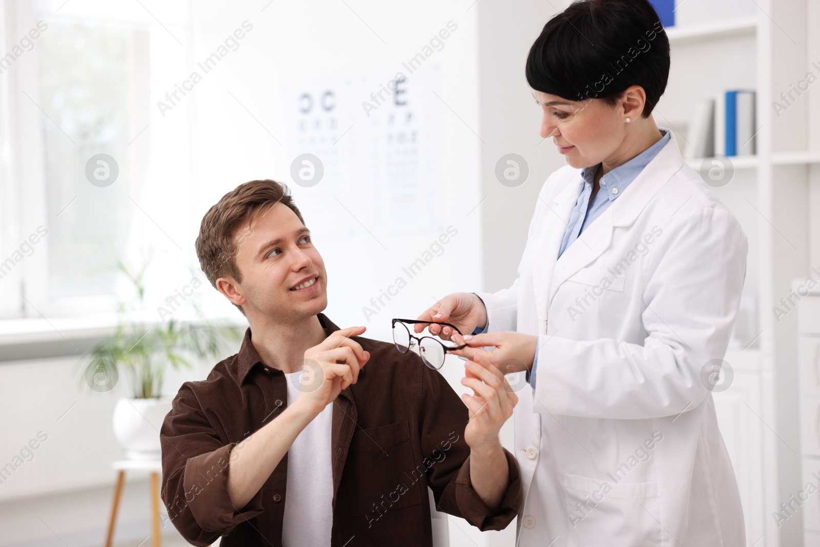 Ophthalmologist giving glasses to patient in clinic Photo of Ophthalmologist giving glasses to patient in clinic