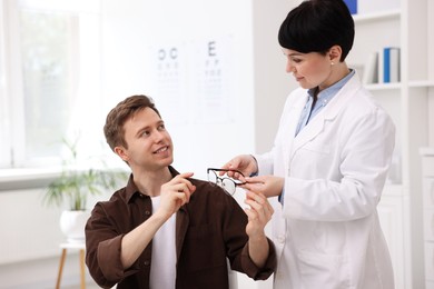 Photo of Ophthalmologist giving glasses to patient in clinic