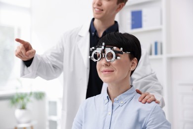 Photo of Ophthalmologist examining patient's vision with trial frame in clinic