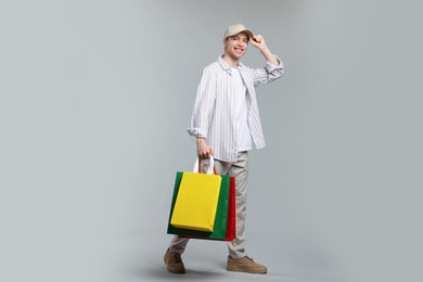 Photo of Cheerful man with shopping bags on light grey background