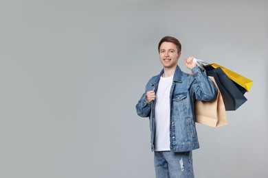 Photo of Cheerful man with shopping bags on light grey background. Space for text