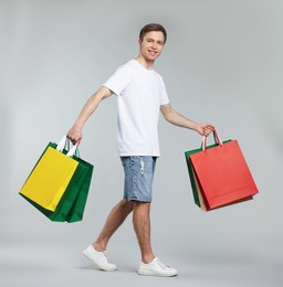 Photo of Cheerful man with shopping bags on light grey background