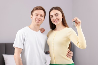 Photo of Happy couple with key of their new house indoors