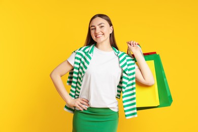 Photo of Positive woman with shopping bags on yellow background