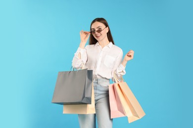 Photo of Positive woman with shopping bags on light blue background