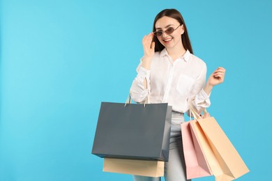 Photo of Positive woman with shopping bags on light blue background. Space for text