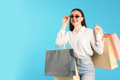 Photo of Positive woman with shopping bags on light blue background. Space for text
