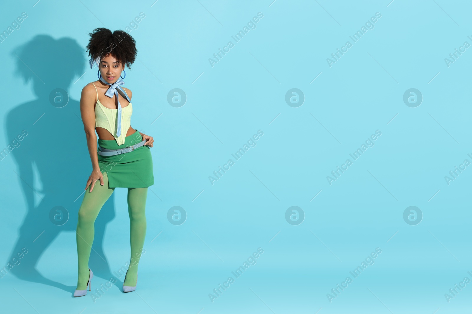 Fashionable portrait of beautiful Brazilian woman in stylish outfit on light blue background. Space for text Photo of Fashionable portrait of beautiful Brazilian woman in stylish outfit on light blue background. Space for text