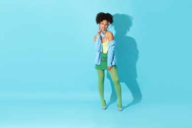 Photo of Fashionable portrait of beautiful Brazilian woman in stylish outfit on light blue background. Space for text
