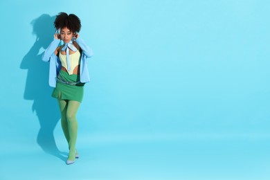 Photo of Fashionable portrait of beautiful Brazilian woman in stylish outfit on light blue background. Space for text